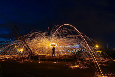 Silhouette man making wire wool against sky at night