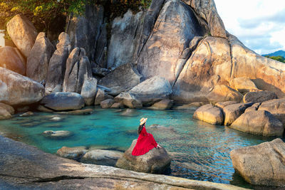 Rear view of man sitting on rock