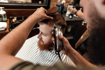 Barber trimming hair of customer