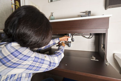 Close-up of woman repairing bathroom sink