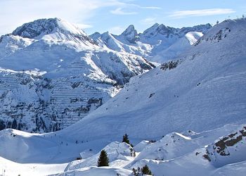 Scenic view of snow covered mountains against cloudy sky