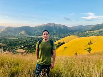 Portrait of man standing on field against mountains