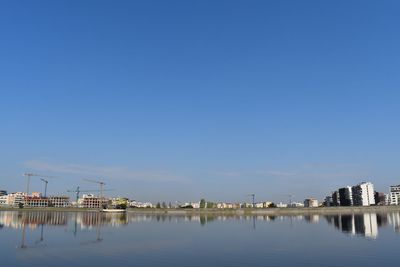 Reflection of buildings in lake against blue sky