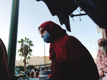 Side view of man standing by car against sky