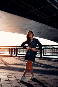 A woman is standing under a bridge