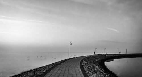 Footpath by sea against sky