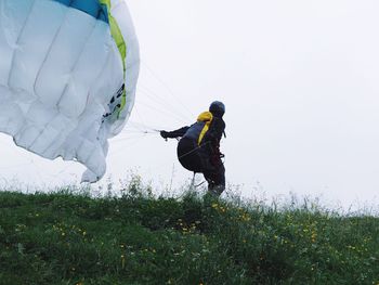 Woman paragliding on field against sky