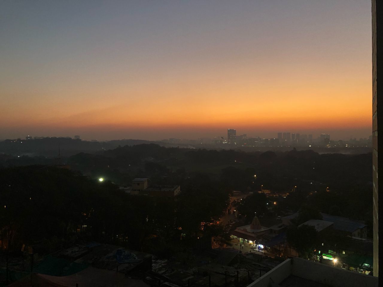 HIGH ANGLE VIEW OF ILLUMINATED CITY AT SUNSET