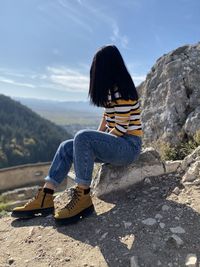Man sitting on rock against mountains