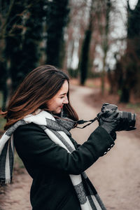 Young woman photographing with camera in forest