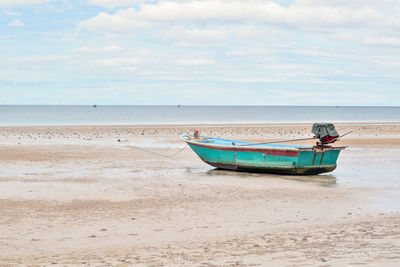 Boat moored on beach against sky