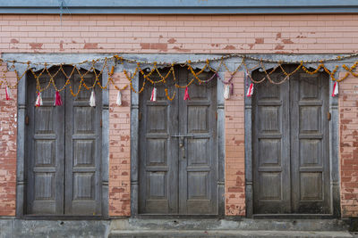 Three beautiful old blue-grey wooden doors decorated with garlands and set in pink brick, bandipur