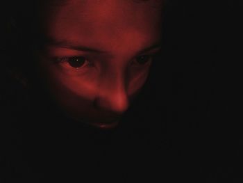 Close-up portrait of young woman against black background