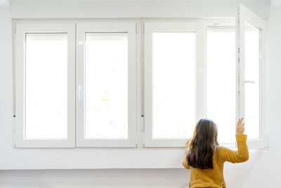 Rear view of woman standing against window