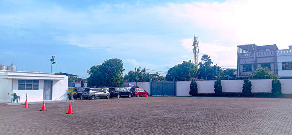 Cars on street by buildings against sky