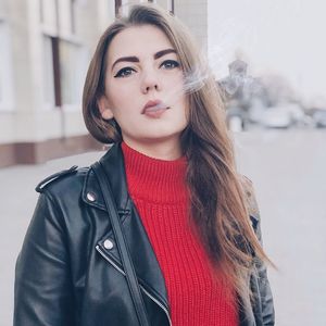 Portrait of beautiful young woman smoking on city street