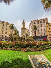 Statue by buildings against sky in city