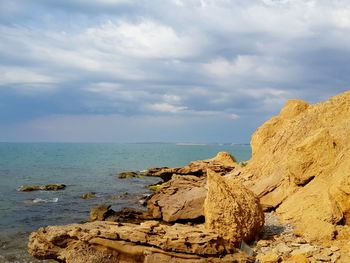 Rock formation on beach against sky