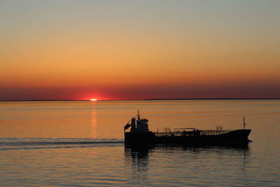 Silhouette boat in sea against sky during sunset