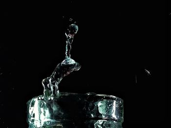 Close-up of water splashing from glass against black background