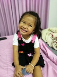 Portrait of cute girl sitting on bed at home