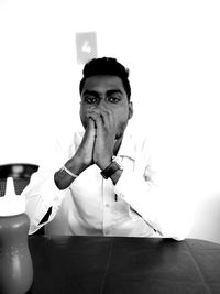 Portrait of young man sitting against wall