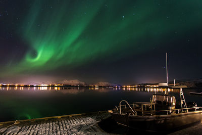 Boat moored at harbor against sky at night