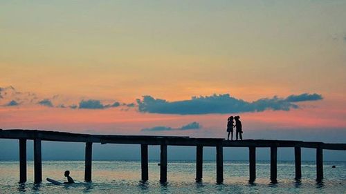 Pier in sea at sunset