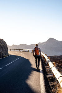 Sporty girl with backpack walking on a lonely road


