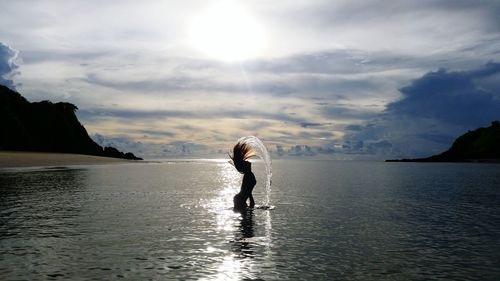 Silhouette of woman taking bath in lake