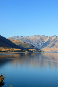 Scenic view of lake and mountains against clear blue sky