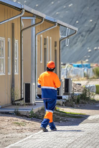 Rear view of man walking on street against buildings in city