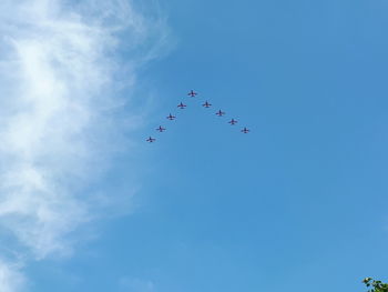 Low angle view of birds flying against blue sky