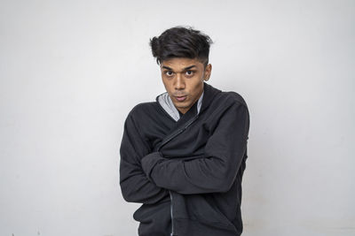 Portrait of young man standing against white background
