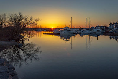 Sailboats moored in lake against sky during sunset