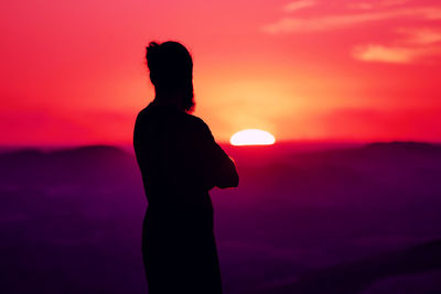Silhouette man standing against orange sky during sunset
