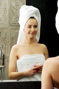 Reflection of woman wearing towel in mirror at bathroom