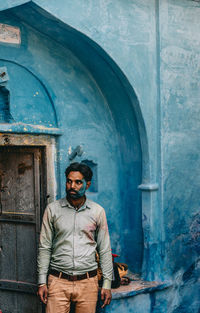 Portrait of man wearing sunglasses standing against wall