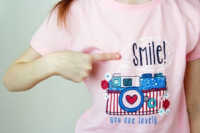 Midsection of woman pointing at smile text on t-shirt
