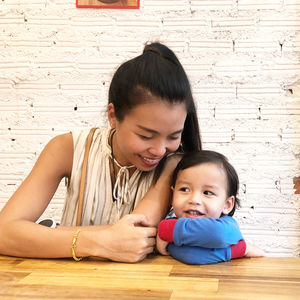 Happy mother and son sitting against wall