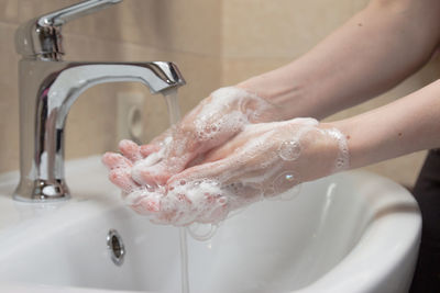 Cropped hands washing faucet