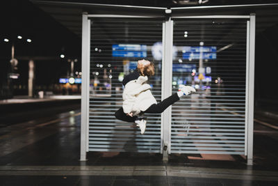 Side view of woman jumping on street at night