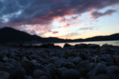 Surface level of rocks at beach against sky during sunset