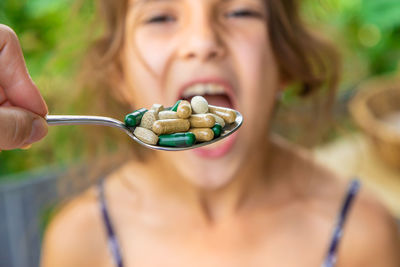 Hands of woman holding spoon of medicine in front of girl