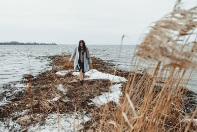 Woman standing by sea against sky