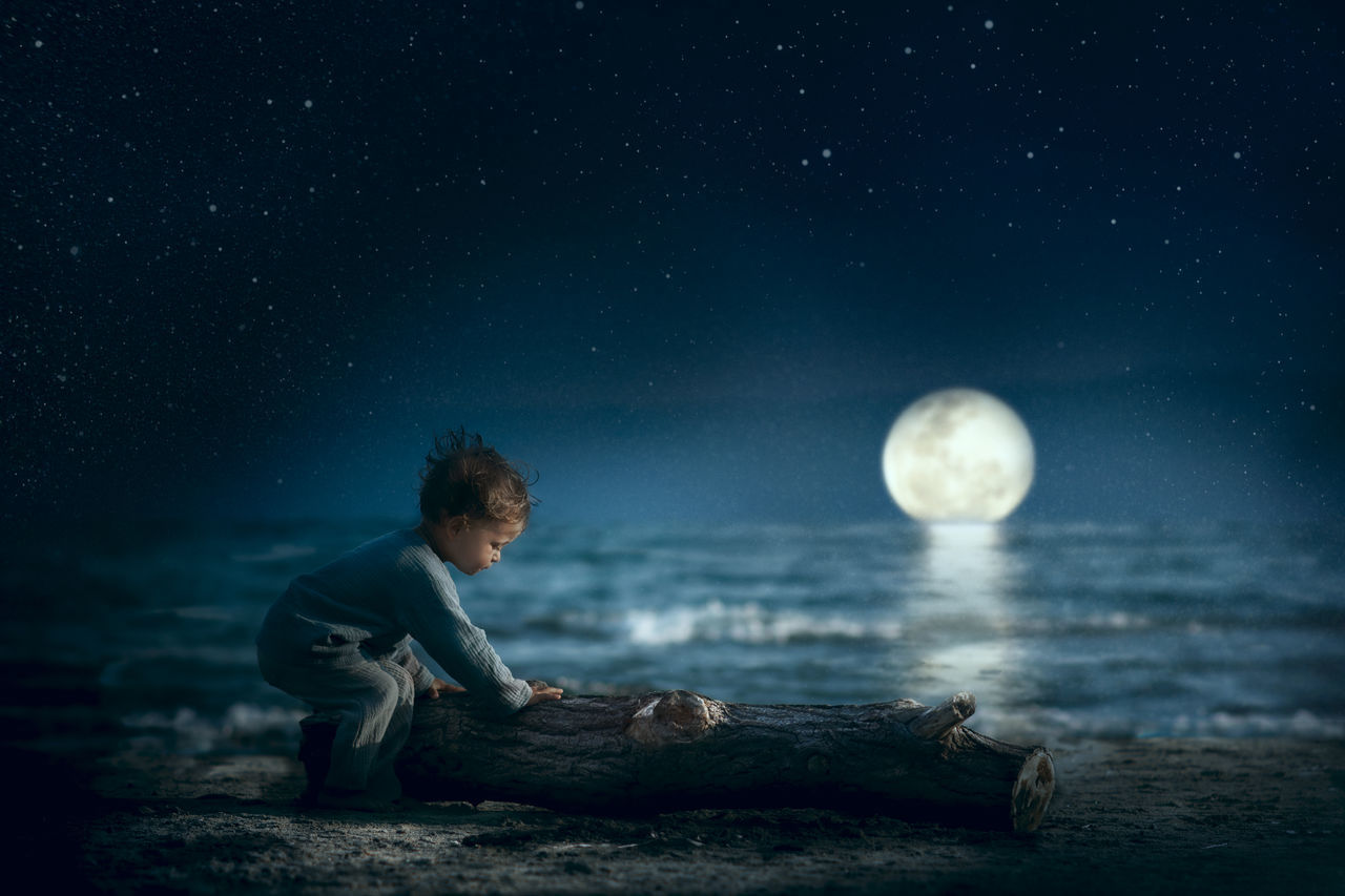 night, full length, water, men, males, real people, sea, sitting, leisure activity, one person, nature, sky, childhood, boys, child, star - space, lifestyles, astronomy, outdoors, moonlight, innocence, digital composite