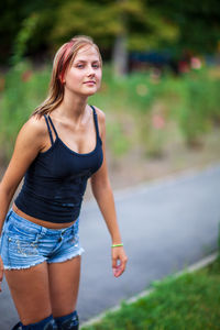 Young woman looking away while standing against blurred background