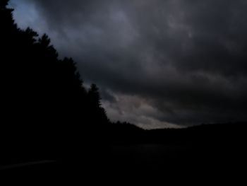 Silhouette of trees against cloudy sky