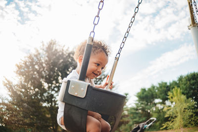 Cute boy sitting on swing at playground