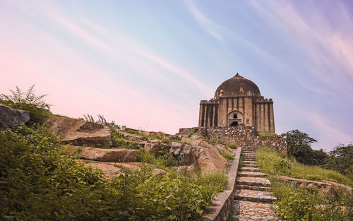 View of adham khan's tomb against sky during sunset